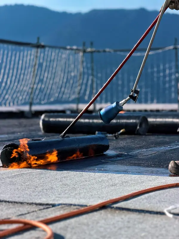 Rouleau de bitume enflammé au chalumeau sur une toiture-terrasse
