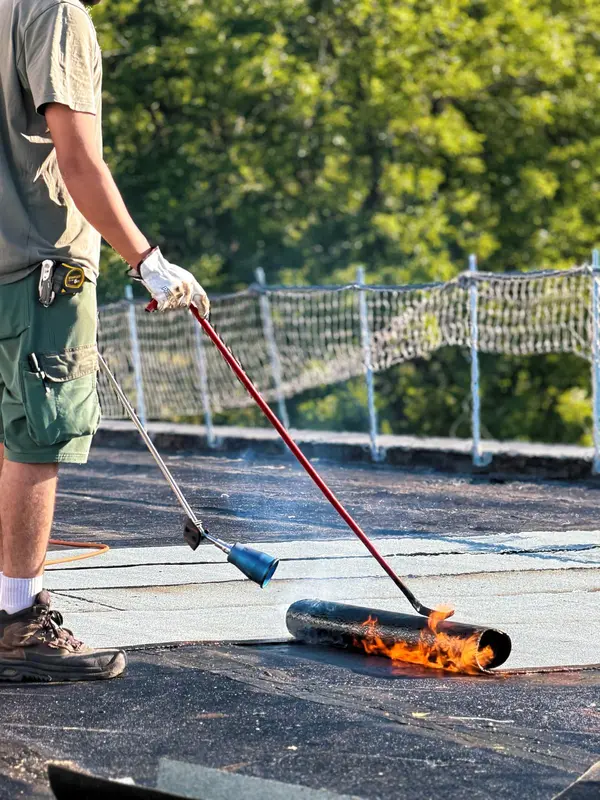 Soudage au chalumeau d'un rouleau de bitume par un ouvrier STRED Swiss